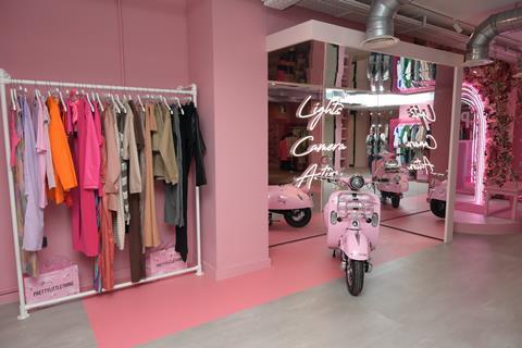 Interior of PrettyLittleThing, London, showing clothes on display, a pink motorbike and a mirror with the words: 'Lights, camera, action'